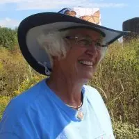 Rhonda Brady wearing a monarch butterfly hat in a prairie field