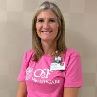 Jody Henry smiles in a pink OSF HealthCare T-shirt with an OSF badge clipped to the collar