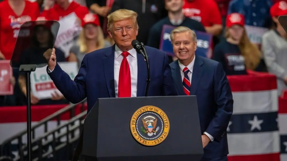 Senator Lindsey Graham smiles behind President Trump at the rally in the Bojangle's Coliseum Charlotte^ North Carolina - 2 March 2020
