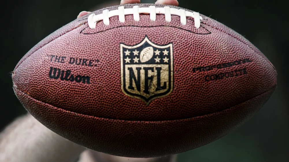 NFL professional athlete holds a ball for American football.