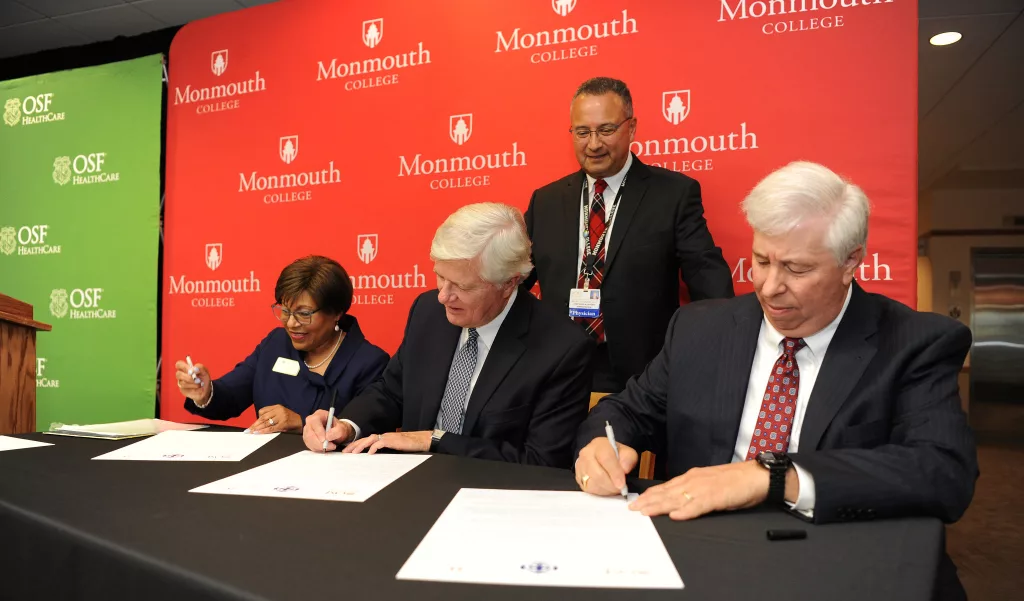 OSF HealthCare and Monmouth College have established the Monmouth College - OSF 3+1 nursing program. Signing the agreement at a ceremony Thursday at Monmouth College were, from left: Dr. Charlene Aaron, President, OSF Colleges of Nursing; Monmouth College President Clarence Wyatt; and Robert Sehring, CEO, OSF HealthCare. In the back is Dr. Ralph Velezquez, System Chief Medical Officer, OSF HealthCare and a member of the Monmouth College Board.