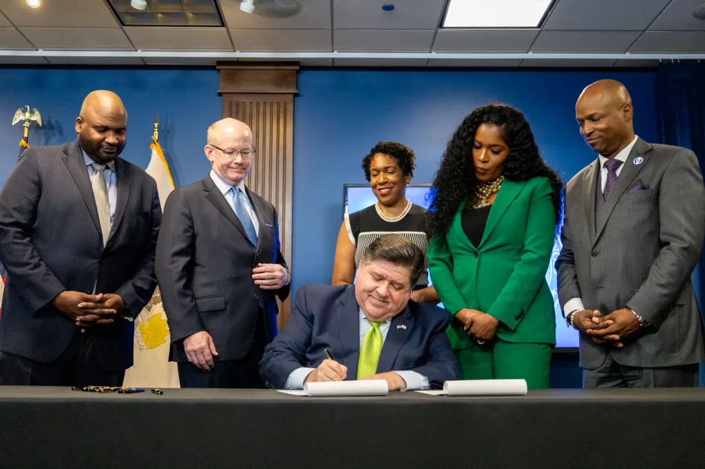 Flanked by the lieutenant governor and legislative leaders, Gov. JB Pritzker signs the $53.1 billion fiscal year 2025 state budget into law after months of negotiations. (Capitol News Illinois photo by Andrew Adams)