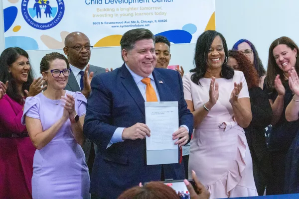 Gov. JB Pritzker holds up Senate Bill 1 after signing it into law, flanked by Reps. Mary Beth Canty, D-Arlington Heights, and Will Davis, D-Homewood (left) and lead Senate sponsor Sen. Kimberly Lightford, D-Maywood (right). Pritzker said the agency is expected to be up and running in 2026. (Capitol News Illinois photo by Dilpreet Raju)