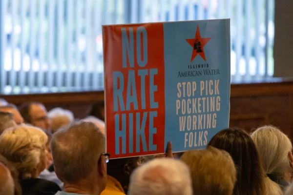 An attendee opposed to water rate increases holds up a sign at a public hearing hosted by the Illinois Commerce Commission in Bolingbrook. (Capitol News Illinois photo by Andrew Adams)
