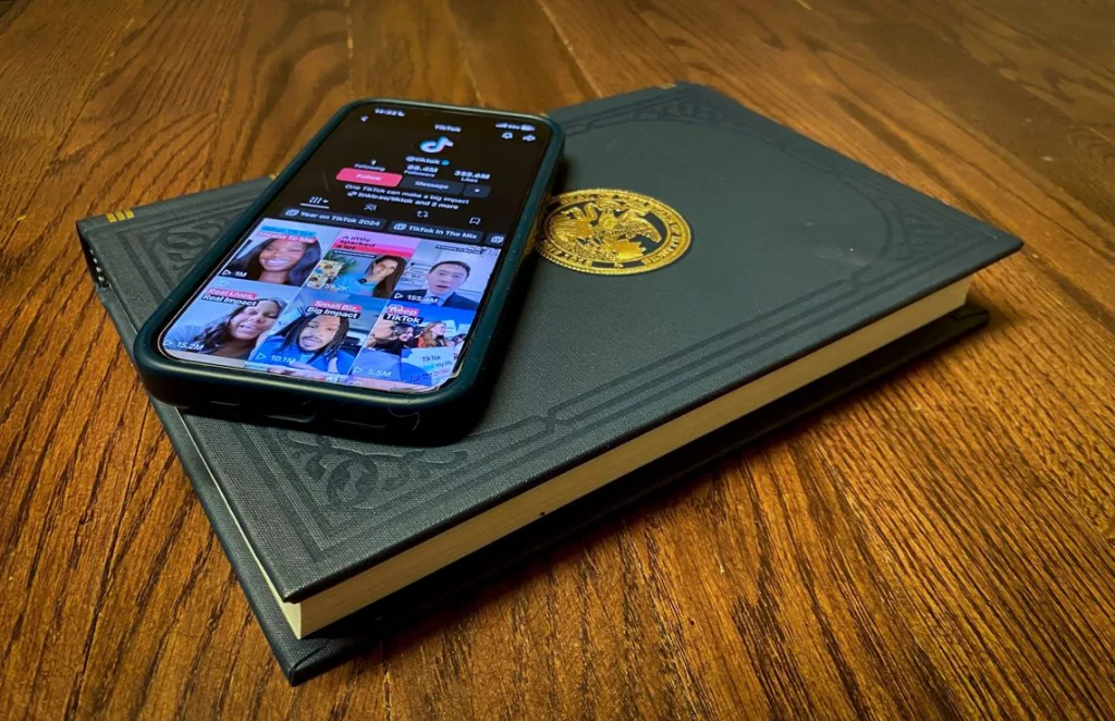 A phone sitting on an “Illinois Blue Book” shows the official profile of TikTok onits app. 