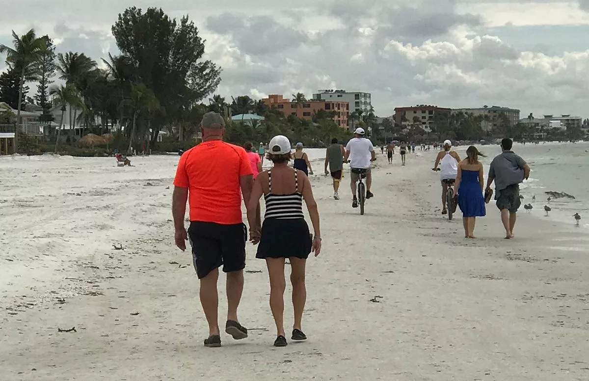 Steve and Christine Youngquist walk hand-in-hand on a beach.