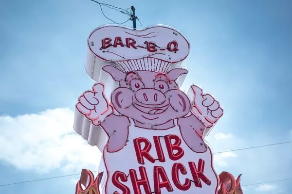 Neon sigh of a big with his thumbs up, wearing a white apron and chef's hat