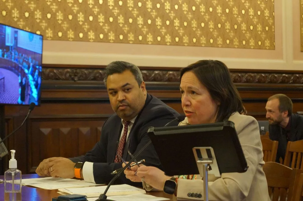 Sen. Christina Castro, right, and Samir Tanna, deputy legislative director for Gov. JB Pritzker, testify before a Senate committee Tuesday on a bill that would require all school districts in Illinois to adopt policies restricting cell phone use in classrooms. (Capitol News Illinois photo by Peter Hancock)