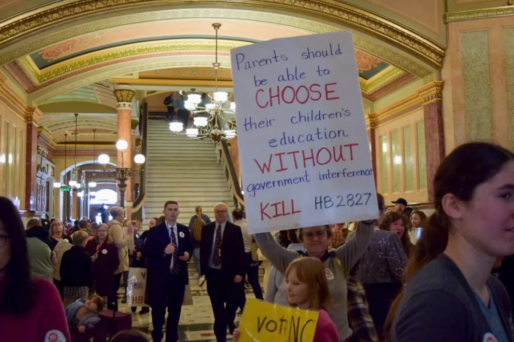 A woman holds a sign, which is just one of the many signs held by the thousands of people who gathered in the Statehouse on Wednesday to oppose a bill relating to homeschoolers. (Capitol News Illinois photo by Jade Aubrey)