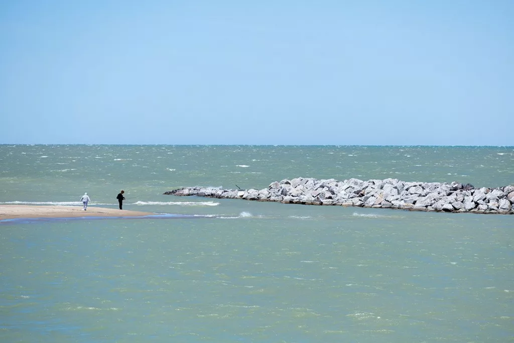 Two people fish on a beach at Illinois Beach State Park near one of 22 breakwaters which protect the shoreline from erosion.