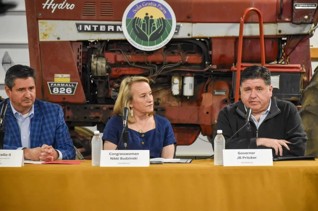 Illinois Gov. JB Pritzker, Congresswoman Nikki Budzinski, and Illinois Department of Agriculture Director Jerry Costello II speak at Sola Gratia Farm in Urbana, Illinois on March 19, 2025. Farmers and environmental leaders were also in attendance to discuss agriculture funding cuts. photo by Jennifer Bamberg, Investigate Midwest
