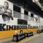 kimbroughs-2: A vibrant mural of Albert and Elbert Kimbrough, frozen in their 1950s football glory, now graces the newly christened Kimbrough Fieldhouse at Galesburg Jr./Sr. High School, unveiled during a heartfelt dedication ceremony on Sunday, May 25, 2025. (JAY REDFERN/WGIL)