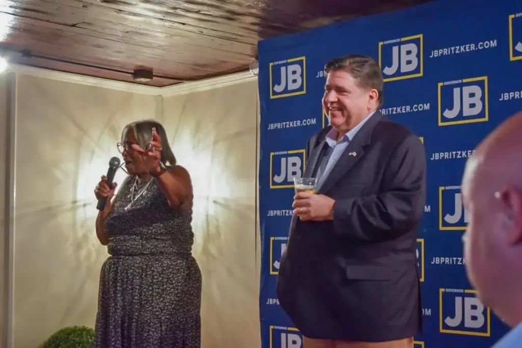 Gov. JB Pritzker holds a branded craft “JBeer” on stage at a Springfield campaign kickoff event alongside local state Sen. Doris Turner. (Capitol News Illinois photo by Jade Aubrey)