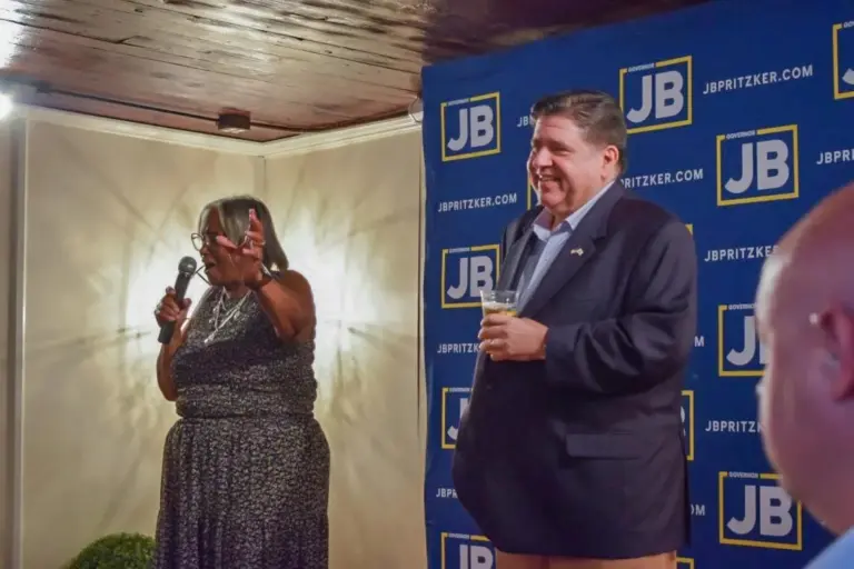 Gov. JB Pritzker holds a branded craft “JBeer” on stage at a Springfield campaign kickoff event alongside local state Sen. Doris Turner. (Capitol News Illinois photo by Jade Aubrey)