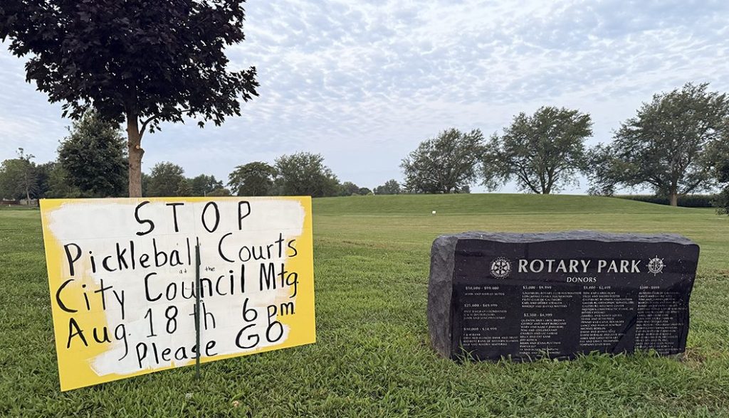 Several signs in opposition of the project could be seen at Rotary Park early Friday morning, saying "Save Our Green Spaces" and "Stop Pickleball Courts" and encouraging attendance at Monday's meeting.