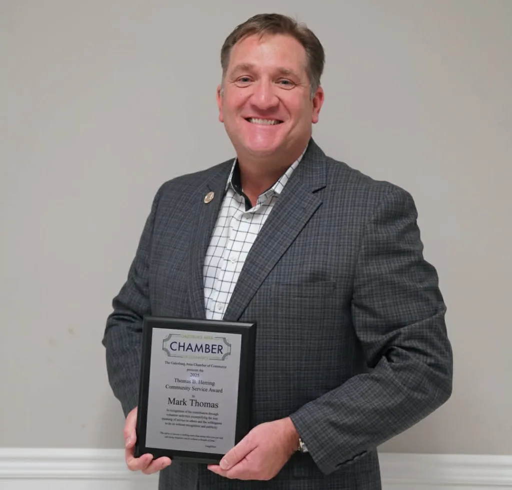 Mark Thomas holds the 2025 Thomas B. Herring Community Service Award plaque after being honored by the Galesburg Area Chamber of Commerce.