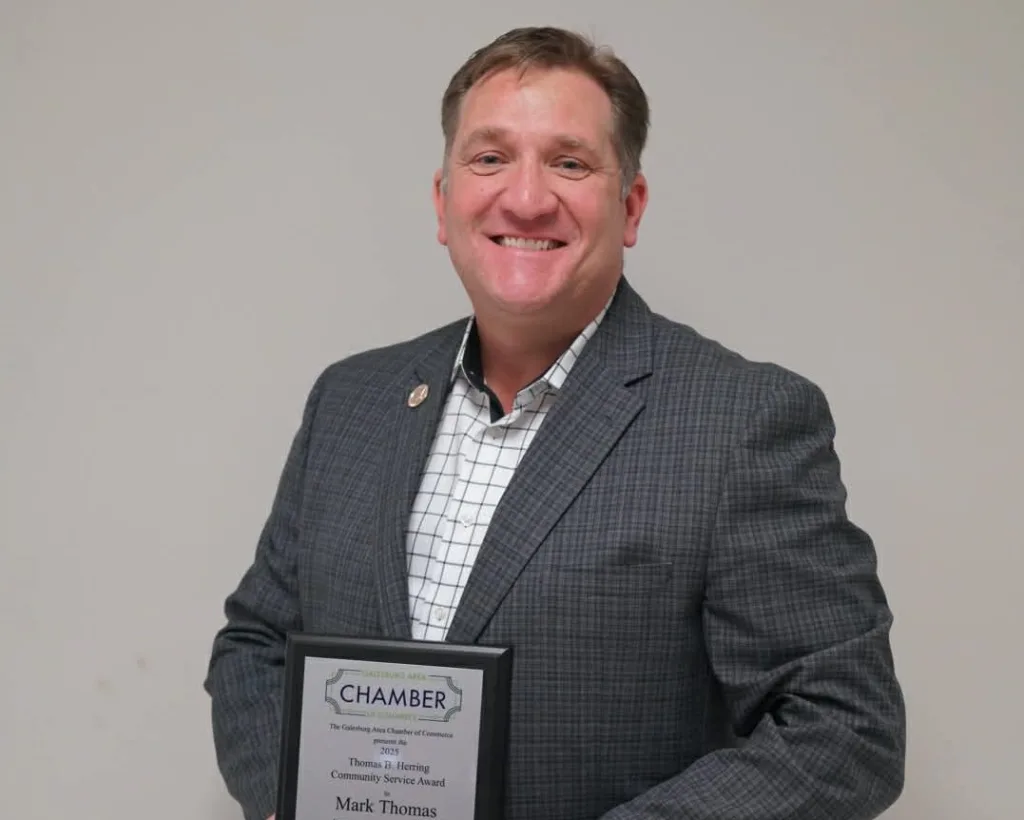 Mark Thomas holds the 2025 Thomas B. Herring Community Service Award plaque after being honored by the Galesburg Area Chamber of Commerce.