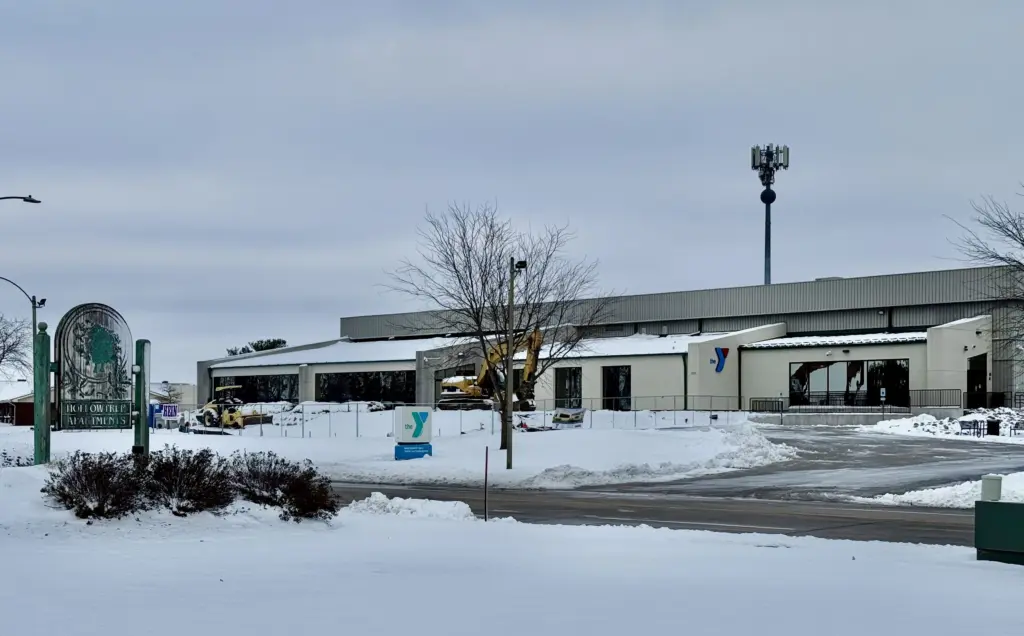 Snow-covered view of the Hollow Tree Apartments sign and the YMCA building along West Carl Sandburg Drive in Galesburg, Illinois, under cloudy skies on Sunday, Nov. 30, 2025.
