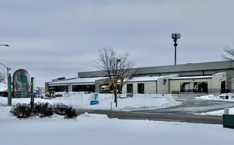 Snow-covered view of the Hollow Tree Apartments sign and the YMCA building along West Carl Sandburg Drive in Galesburg, Illinois, under cloudy skies on Sunday, Nov. 30, 2025.