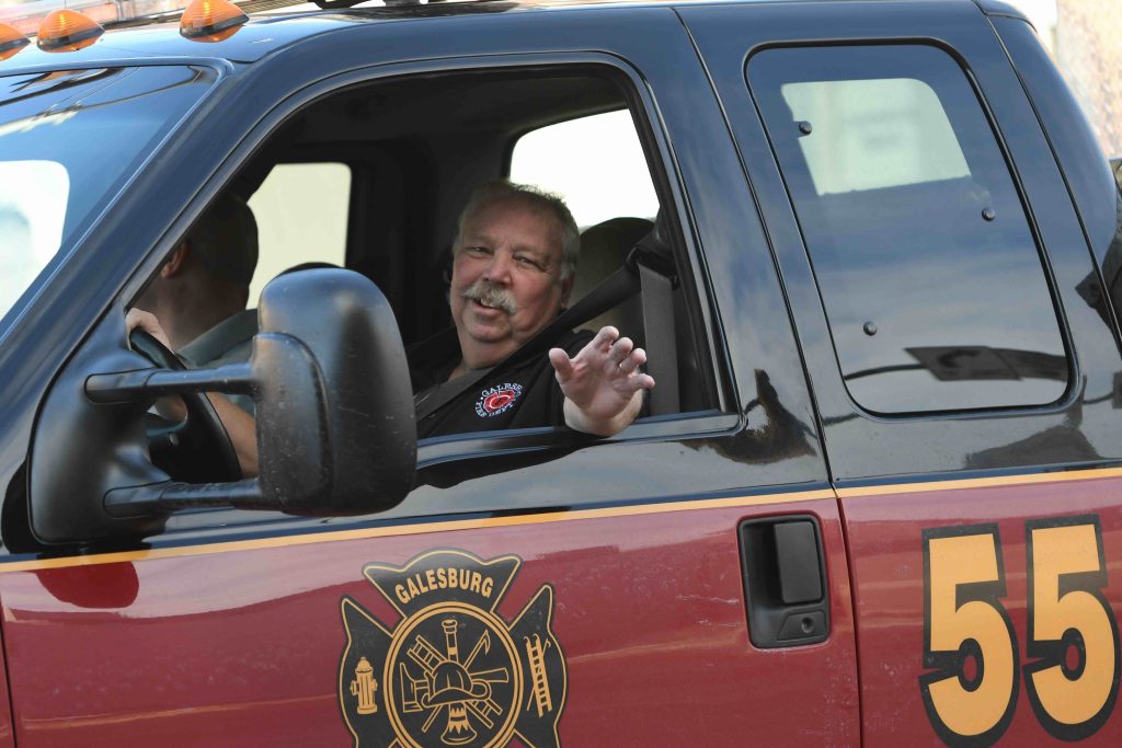 Tom “Baughie” Baughman smiles and waves while driving Galesburg Fire Department Rescue 55. Courtesy photo by Bill Dickerson.