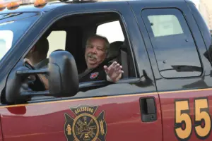 Tom “Baughie” Baughman smiles and waves from the window of a Galesburg Fire Department rescue truck. Courtesy photo by Bill Dickerson.