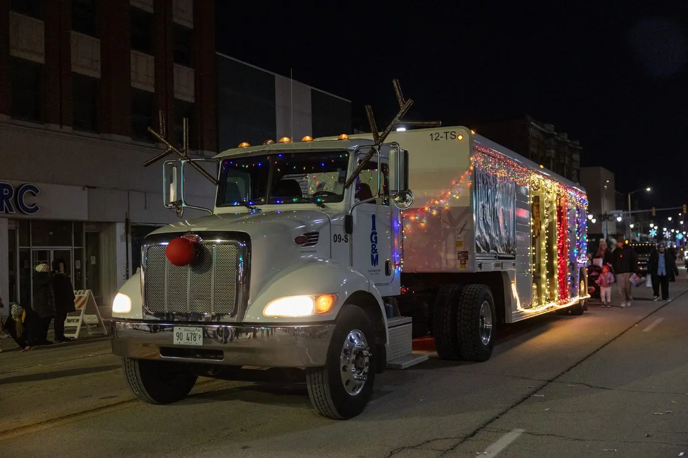Lit-up semi-truck float from G & M Distributors with reindeer antlers, red nose, and colorful lights on the trailer during the 2025 Galesburg Holly Days Parade, with crowds lining the street.(Photo: Steve Davis/seedcophoto.com)