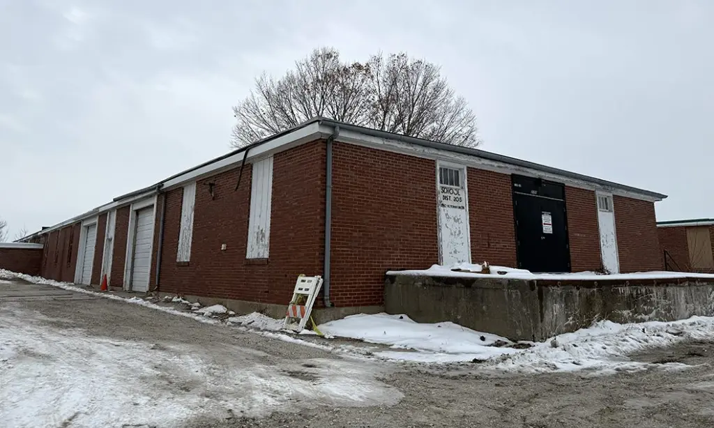 Old Hawthorne Warehouse at 2150 Veterans Drive, Galesburg – brick industrial building with multiple garage doors, now listed for sale by Galesburg CUSD 205.