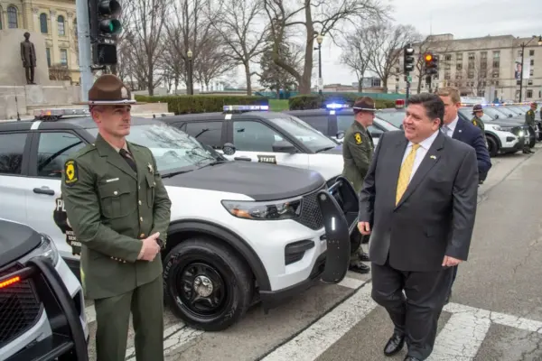 Gov. JB Pritzker passes in front of a row of Illinois State Police vehicles during a ceremony outside the Illinois Capitol in Springfield on March 30, 2022. (Capitol News Illinois photo by Jerry Nowicki)