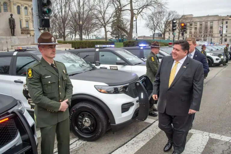 Gov. JB Pritzker passes in front of a row of Illinois State Police vehicles during a ceremony outside the Illinois Capitol in Springfield on March 30, 2022. (Capitol News Illinois photo by Jerry Nowicki)