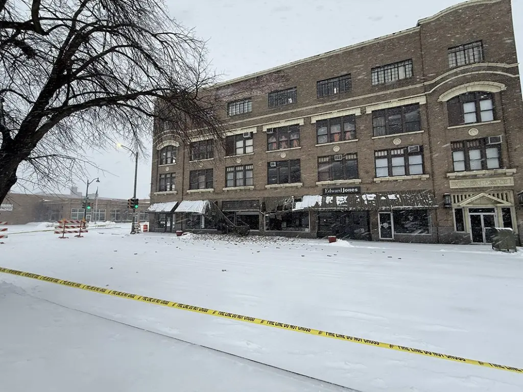 Close-up of broken windows and damaged awnings at ground level of Weinberg Arcade building after brick facade fell.