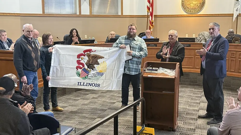 Veteran Byron Baird with parents Doug and Nancy Baird and Rep. Dan Swanson holding Illinois flag at Galesburg City Council veteran honor ceremony