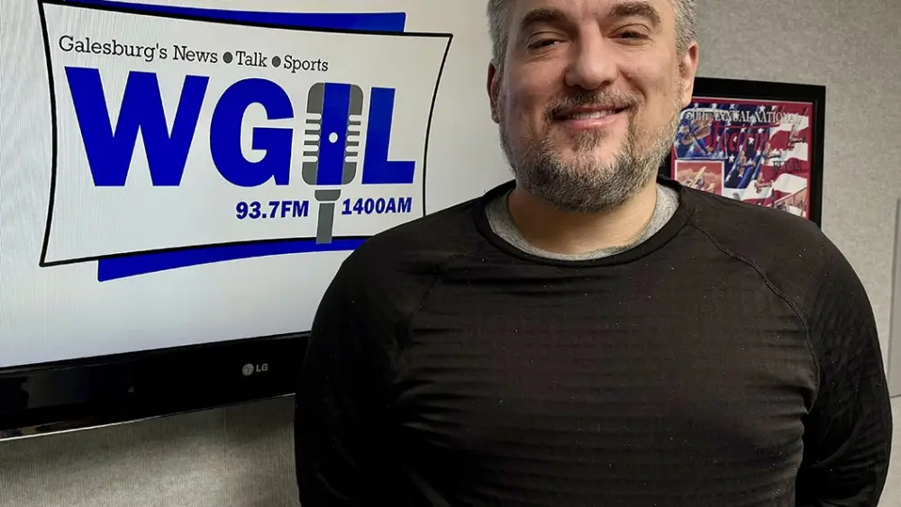 Galesburg Mayor Peter Schwartzman smiling in front of WGIL sign during radio interview