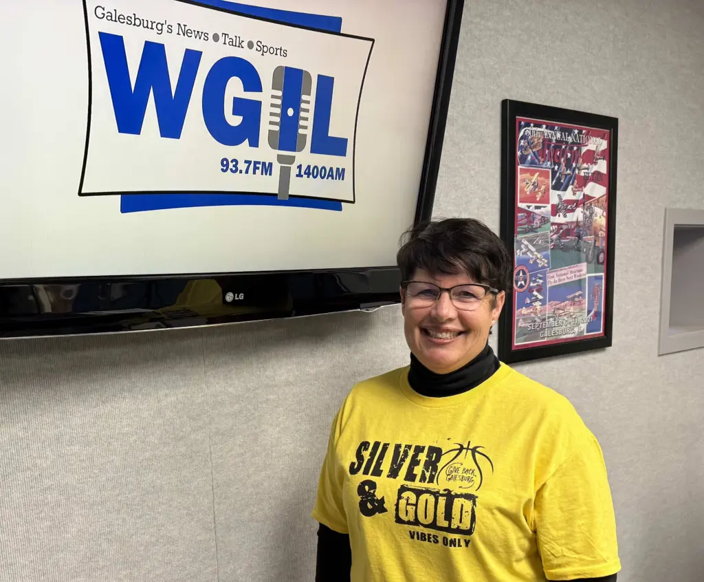 Laurie Aten in WGIL studio wearing Gold Out t-shirt, previewing Galesburg girls basketball fundraiser for Kleine Pediatric Wellness Center.