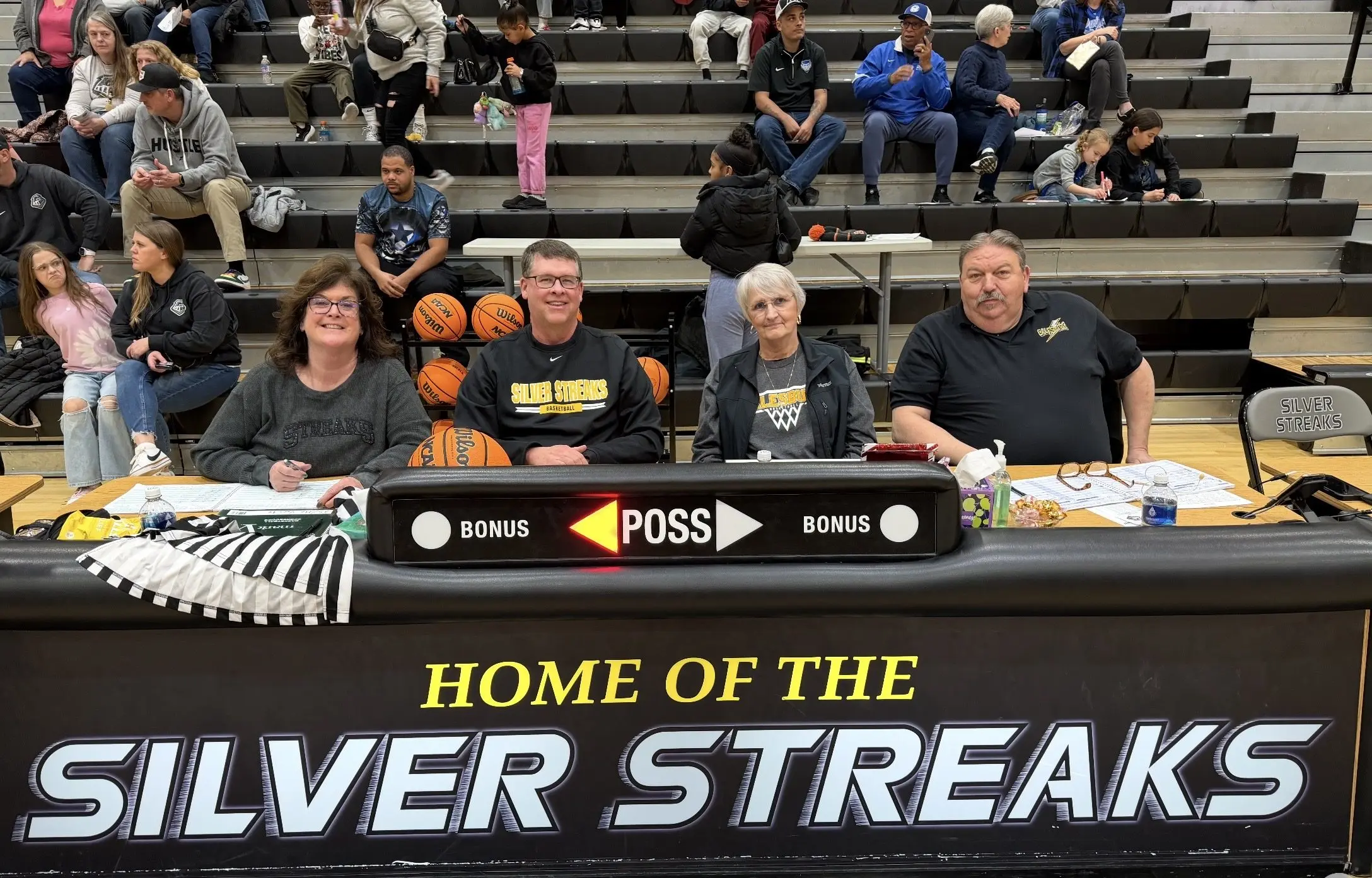 Marla Clay, Brett Wolfe, Jeanine Bryant, and Jeff Lamb seated at the scorer's table at Galesburg High School's Thiel Gym