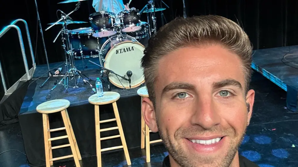 Singer Chris Ruggiero performing on stage with his name displayed behind him