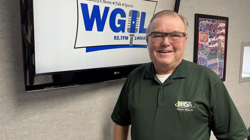 Joe Thompson standing in the WGIL studio wearing an IHSA State Finals shirt