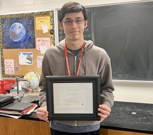 Galesburg High School senior Liam Dilley holds his National Merit Scholarship Certificate of Merit in a classroom at GHS.