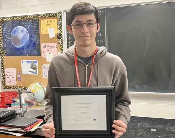 Galesburg High School senior Liam Dilley holds his National Merit Scholarship Certificate of Merit in a classroom at GHS.