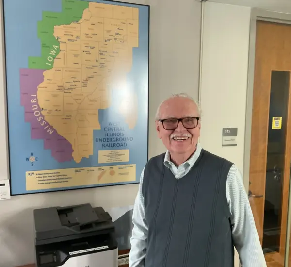 Owen Muelder standing beside the West Central Illinois Underground Railroad map at Knox College in Galesburg, Illinois