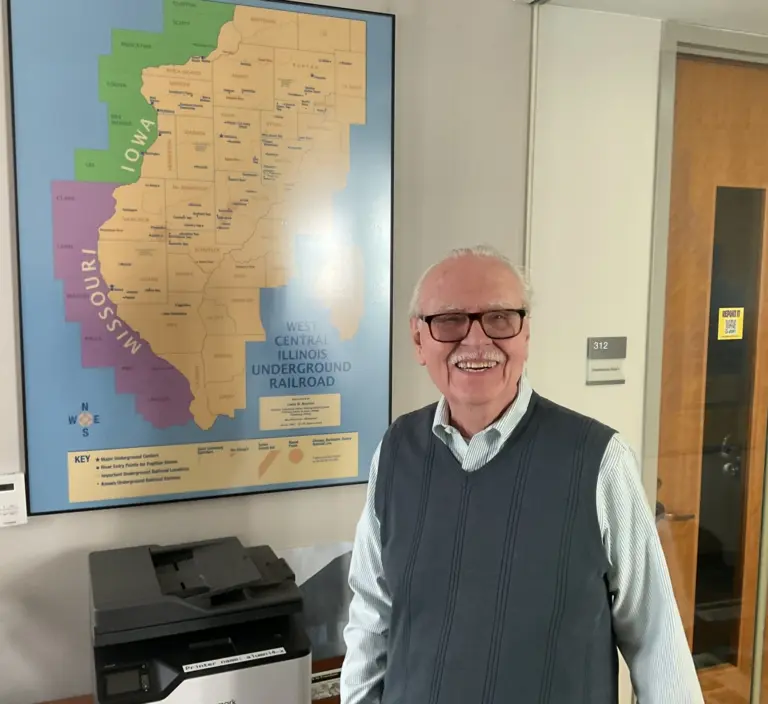 Owen Muelder standing beside the West Central Illinois Underground Railroad map at Knox College in Galesburg, Illinois