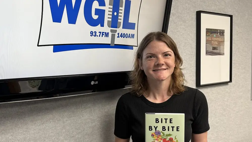 Kayla Whitmer holds a copy of Bite by Bite at the WGIL studio during Galesburg's Morning News