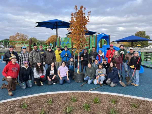 Volunteers gather around a newly planted Fall Fiesta Sugar Maple at Cooke Park in Galesburg, Illinois, during a 2025 tree planting event.