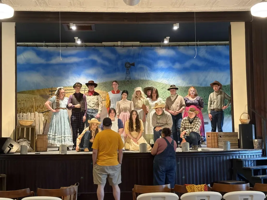 Youth cast in costume on stage during a rehearsal at Ransom Memorial Library Hall in Altona