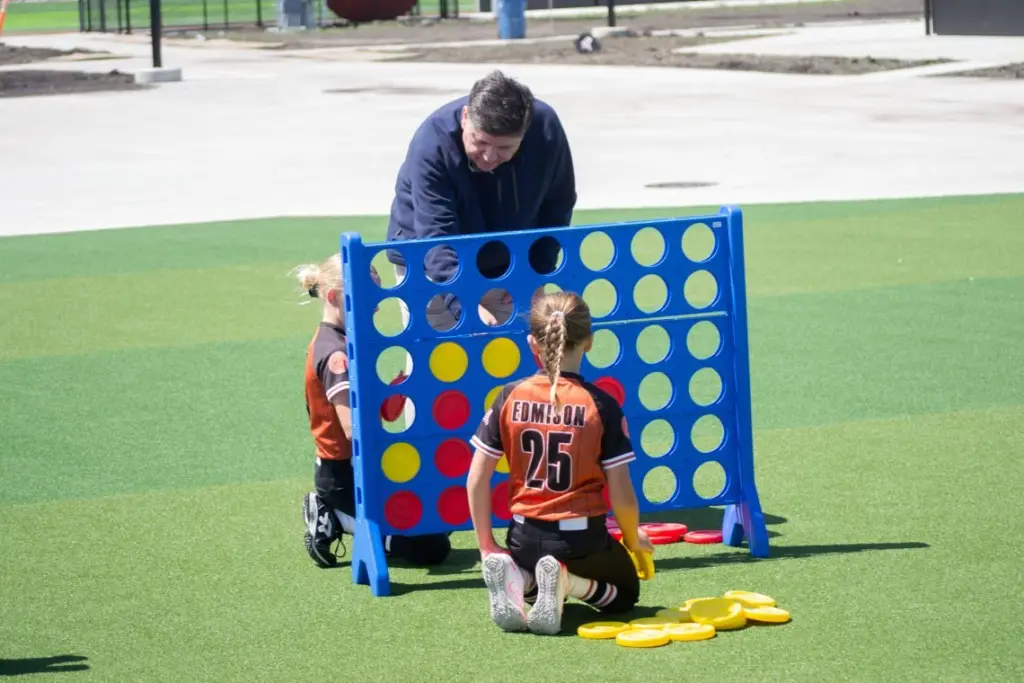 Gov. JB Pritzker plays Connect 4 with children following an event to open a new sports park in Springfield on April 28, 2026.