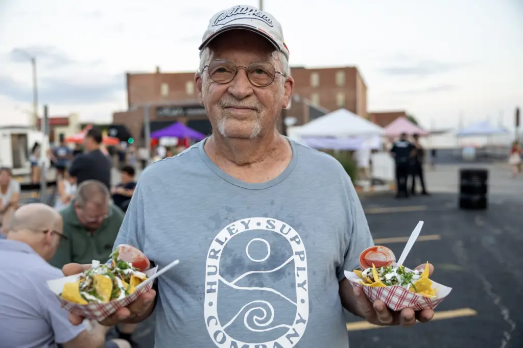 Man in glasses holding two trays of nachos at Taste of Galesburg