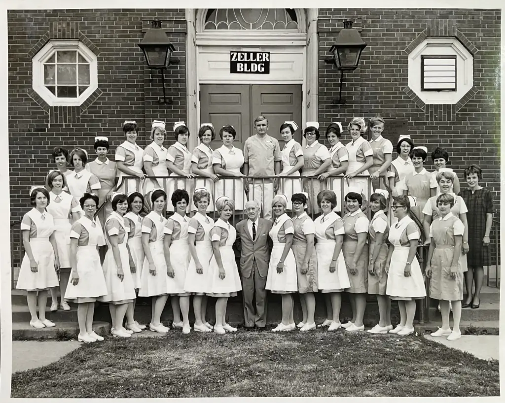 Black and white photo of Cottage School of Nursing students and staff in uniform outside the Zeller Building