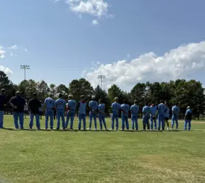Galesburg Post 285 baseball players and coaches standing in a line on the field during the state tournament.