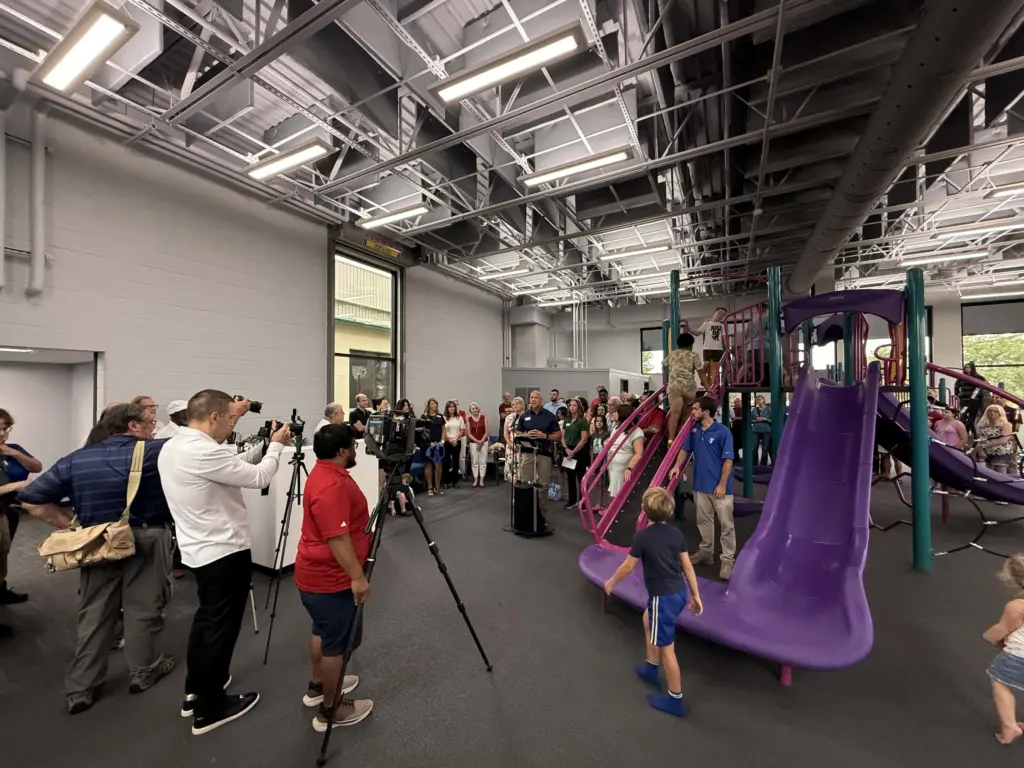 A crowd and news photographers gather as Knox County YMCA CEO Adam Sampson speaks during a ribbon-cutting ceremony.
