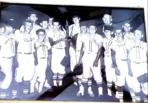 Black-and-white photo of a Little League all-star team holding a trophy, wearing jerseys from multiple teams