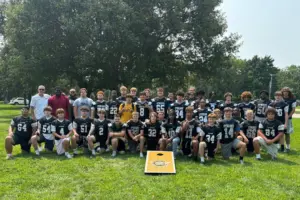 Galesburg Silver Streaks football players and coaches posing together on a grass field